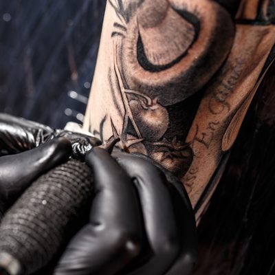 Close up tattoo artist demonstrates the process of getting black tattoo with paint